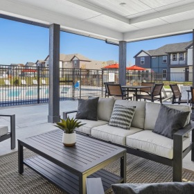 Enjoy your day under the covered outdoor lounging area a patio with a table and chairs